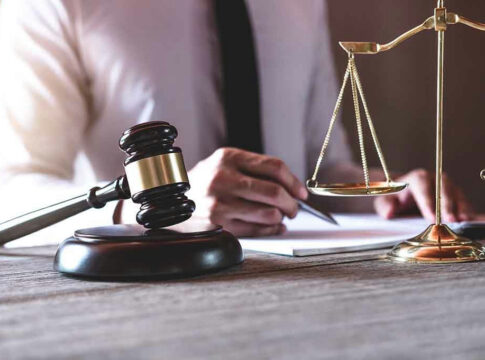 Gavel and scales beside a person writing.