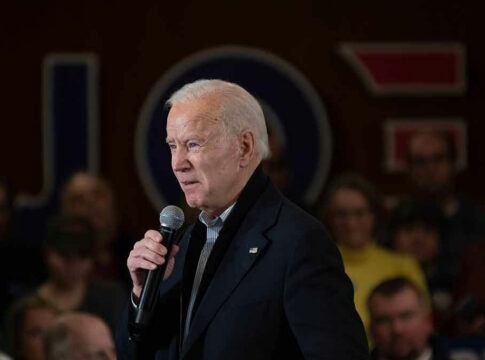 Man speaking into microphone at crowded event.