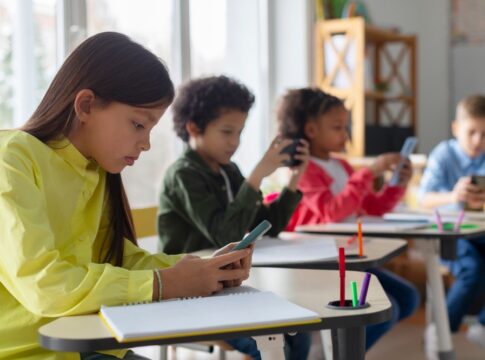 Students using smartphones at classroom desks