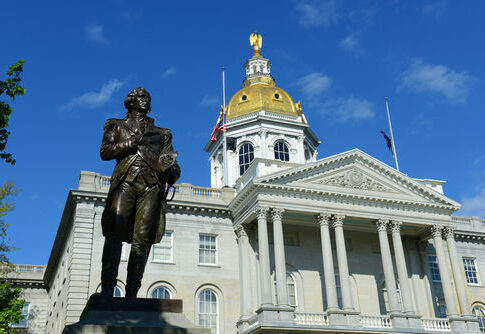 New Hampshire State House with statue in foreground.