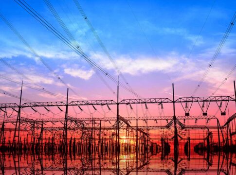 Electrical substation and power lines at sunset with vivid sky and reflections